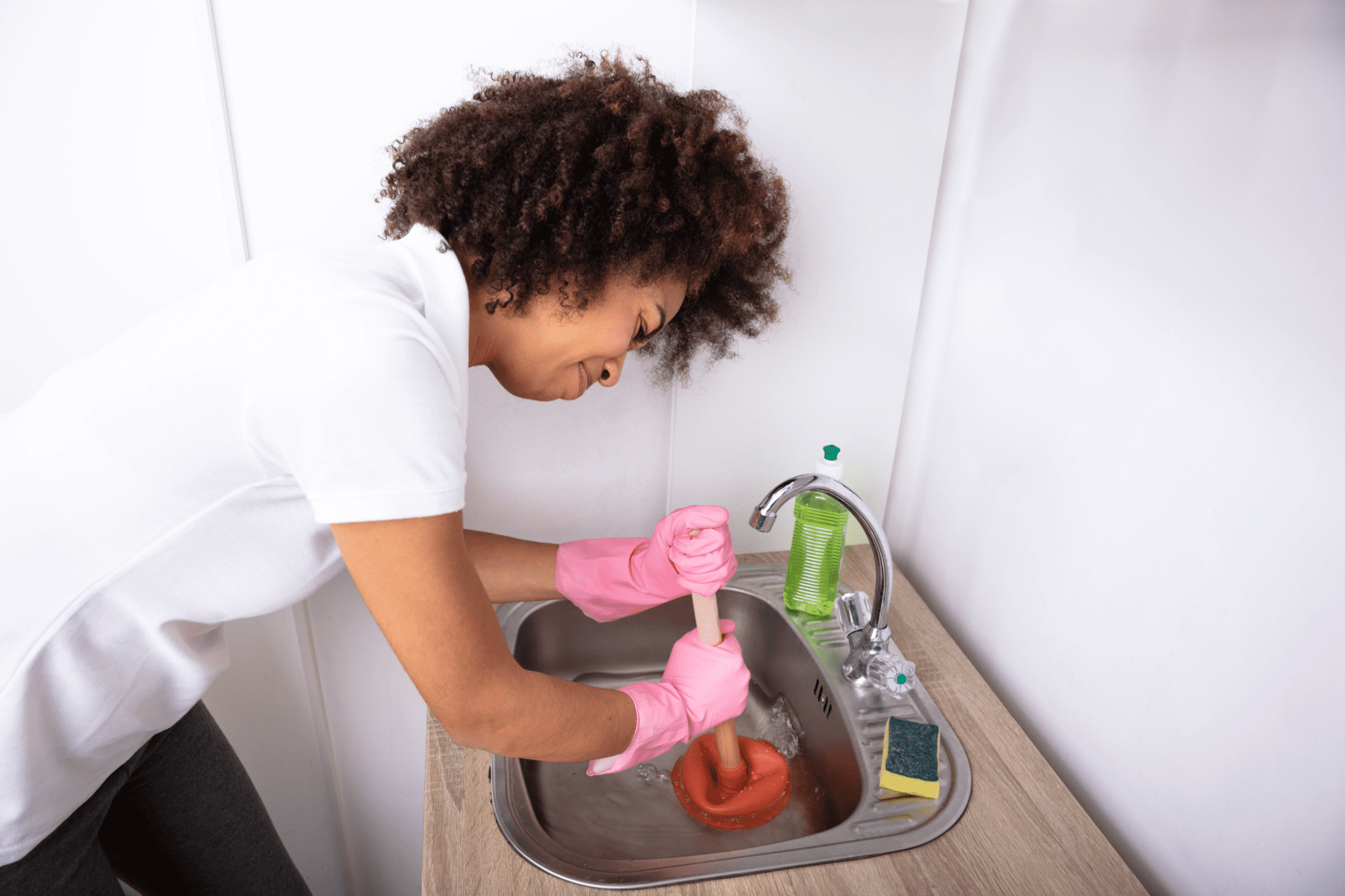 A woman in pink gloves is washing dishes.