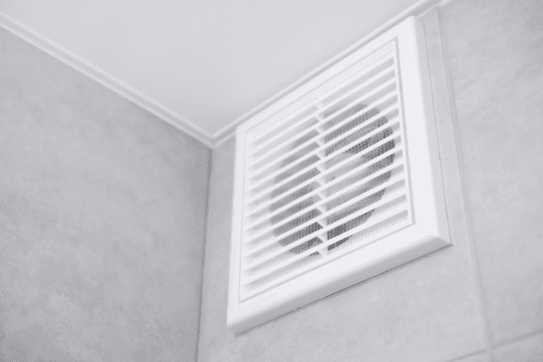 A white air vent in the corner of a room.