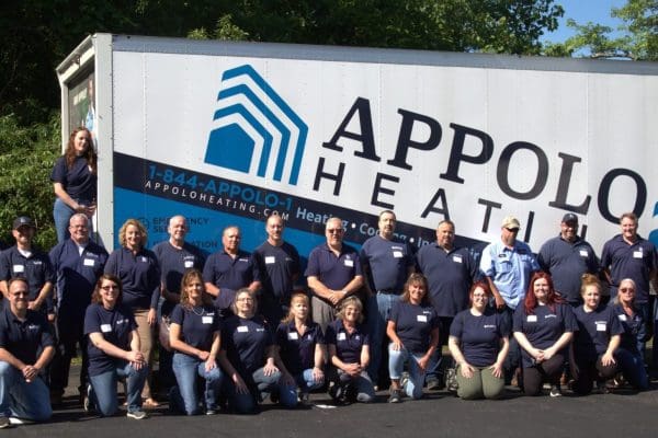 A group of people standing in front of an appo heating sign.