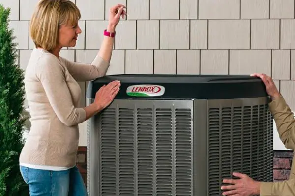A woman is standing next to an air conditioner.