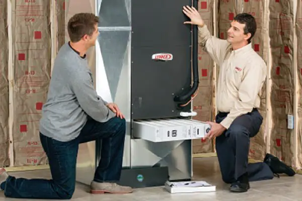 Two men are talking in front of a large refrigerator.